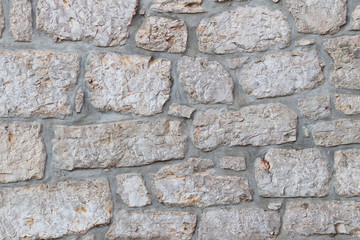 Ancient medieval stone masonry. Texture of a fragment of a wall of an old structure. A background for design and creative work. Decoration and exterior decoration of the building. Construction works
