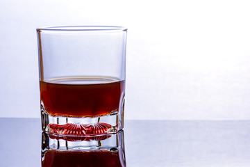 Glass of whiskey on a glass table.