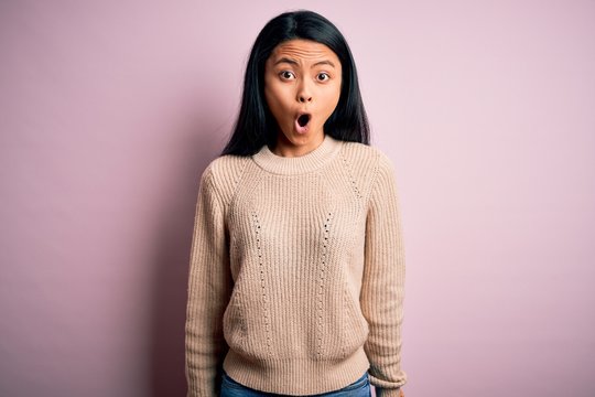 Young beautiful chinese woman wearing casual sweater over isolated pink background afraid and shocked with surprise expression, fear and excited face.