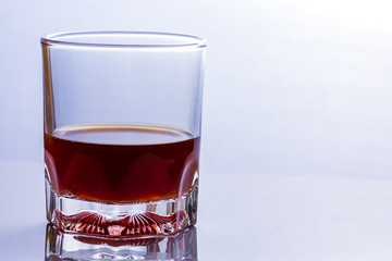 Glass of whiskey on a glass table.