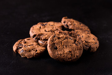 Appetizing chocolate chip cookies with slices of raisins on a black background.