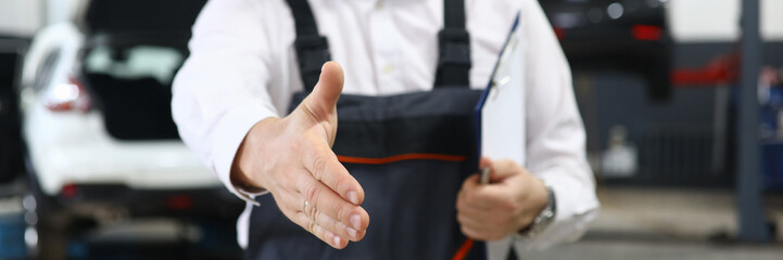 Focus on smart man hand reaching for firm handshake with someone and holding important paper folder with information about different autos. Machinery repairman concept