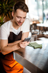 Attractive Caucasian waiter using his cellphone in romantic cafe