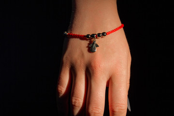 Close-up female hand with red bracelet. Black isolated background.