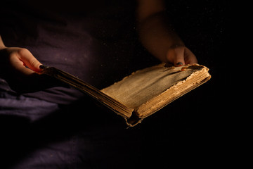 Woman's reading old vintage worn book. Aged ancient holy bible.