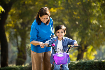 Grandmother with grandson learning to ride bicycle