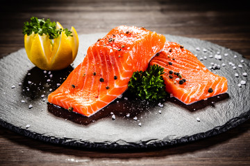 Fresh raw salmon steaks on black stone plate