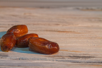 Close up bunch of dried dates on wood. Sweet islamic fruit on white wood.