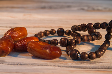 Bunch of dates and bead necklace close up. Wooden bavckground.
