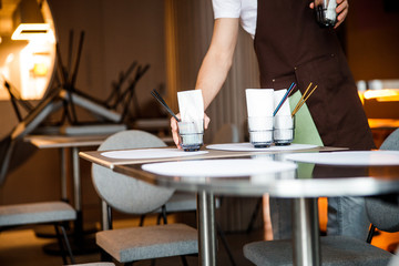 Caucasian waiter lays the table in cafe