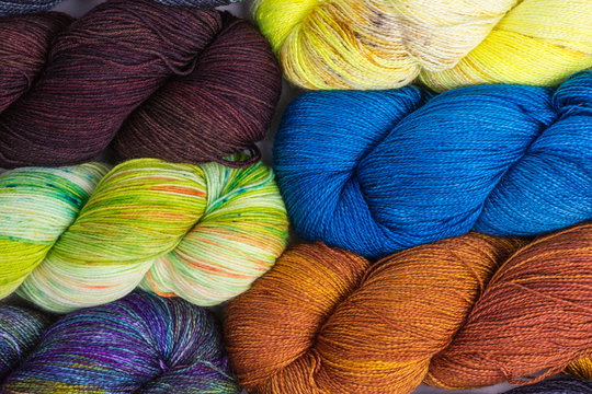 background of multicolored silk and merino wool skeins with yellow, green, blue, brown and purple