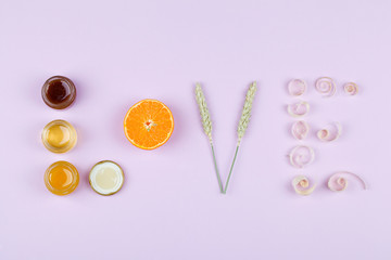 Word love made from jar with honey ,mandarin, wheat and wood shavings on pink background.