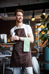 Smiling industrious waiter with napkin working in cafe