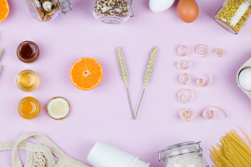 Word love made from jar with honey ,mandarin, wheat and wood shavings on pink background.