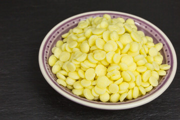 heap of yellow cocoa butter pieces in a bowl - theobroma oil