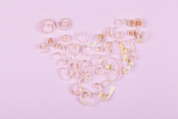 heart from wood shavings on pink background, concept for valentine's day