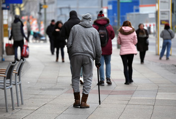 An old man with a sports suit and a walking stick goes for a walk on the Kuhdamm in Berlin Germany...