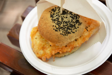 Fresh burger cooked at barbecue outdoors on plastic plate.