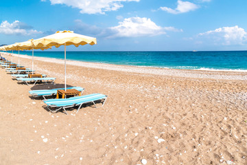 Empty sunbeds and umbrella on Afandou beach near Faliraki (Rhodes, Greece)