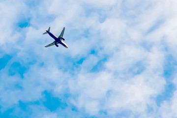 Passenger plane flying in blue sky with white clouds