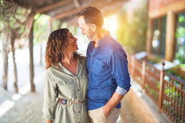 Middle age beautiful couple smiling happy and confident at town park. Standing with smile on face and hugging