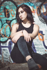Fototapeta na wymiar girl sitting on a background of wall with graffiti