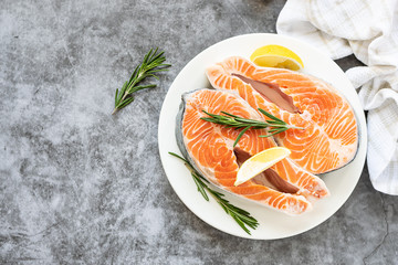 Fresh organic steak of wild salmon with lemon and rosemary on dark stone background with copy space for your text. Sea food concept. Healthy food concept.