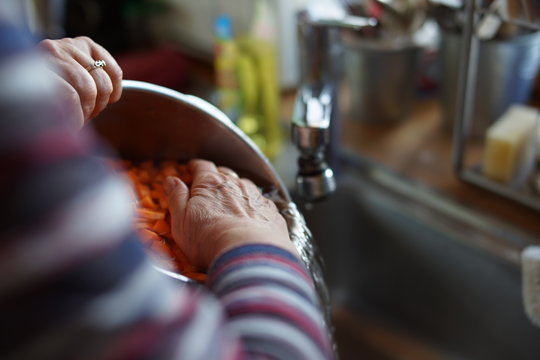 CLOSE-UP OF woman washing sliced carrots