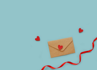 craft paper envelope, red ribbon and red hearts lie on a pastel blue background. Love concept, Valentine's day, Mother's day, International Women's Day, copy space. Flat lay. Horizontal background