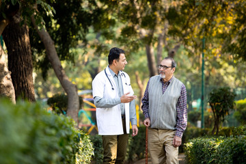 Doctor talking with senior man in hospital garden