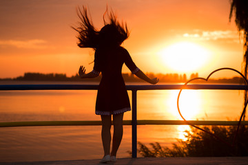 Side view of back light of a woman silhouette breathing deep fresh air at warm sunrise in front of sun. female lightness and airiness