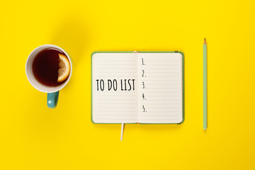 To do list. Mint Tea cup and modern notebook with to do list on bright yellow desk from above