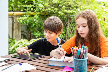Children, boy and girl, learning doing homework and drawing together in garden at home, with tablet