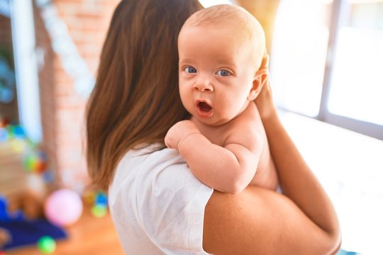 Young beautifull woman and her baby standing at home. Mother holding and hugging newborn