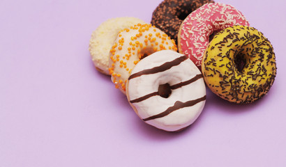 Delicious donuts on violet color background.