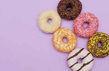 Delicious donuts on violet color background.