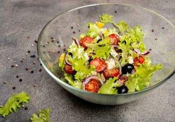 Greek salad with feta cheese, organic black olives, juicy tomatoes, red pepper, red onion, cucumber and lettuce. Close-up.