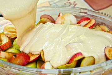 apple pie cooking with cut apples layer filling and liquid dough close up photo