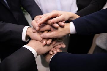 Close up diverse business people stacking hands together showing unity.