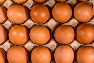 Pile of the hen eggs in paper tray on wooden table. Top view