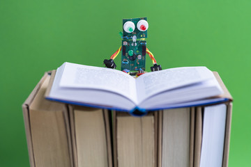 Hand made robot working on the arduino platform with books. Green background. Free space for text. STEM education for children and teenagers, robotics and electronics. DIY. AI. STEAM. Concept.