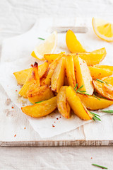 Homemade baked potato fries with rosemary on white wooden board