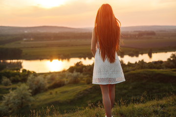 Lonely teen girl looking at sunset in countryside
