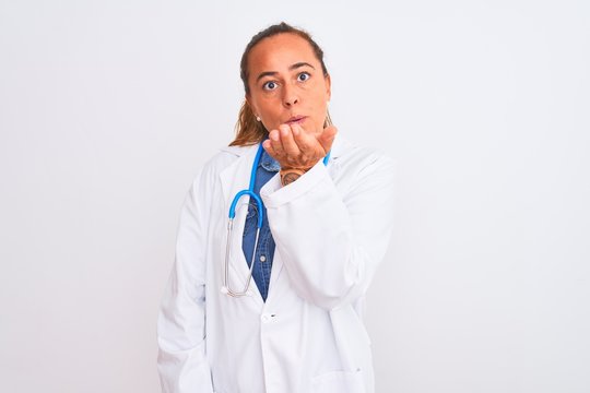 Middle age mature doctor woman wearing stethoscope over isolated background looking at the camera blowing a kiss with hand on air being lovely and sexy. Love expression.