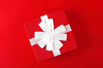 Red gift box present with white bow on a red background. Holiday gift concept, valentines day. Copy space