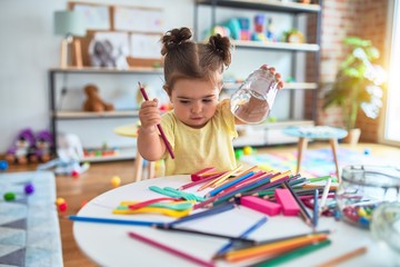 Beautiful toddler standing holding colored pencils at kindergarten