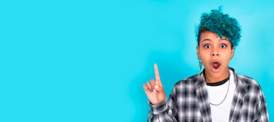 isolated portrait of girl pointing on blue background with astonishment or surprise