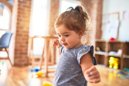 Beautiful toddler standing around lots of toys at kindergarten