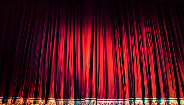 Red Closed Curtain With Spotlight In Theater