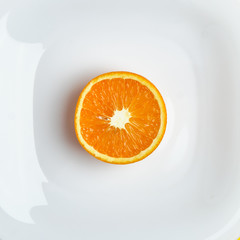 Top view of the half of the orange at the white dish lies on the bright yellow background. Healthy food, detox, diet concept